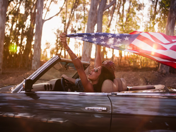 Teenager girl holding an American flag on a road trip